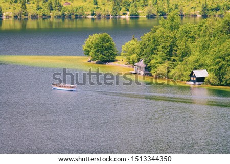 Scenery of touristic tour ship on Bohinj Lake in Slovenia. Nature and Cruise boat on river water in Slovenija. Beautiful landscape view in summer. Alpine Travel destination. Julian Alps mountains