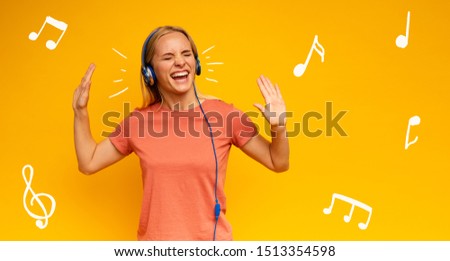 Blonde girl listens to music with headset. Joyful expression on yellow background
