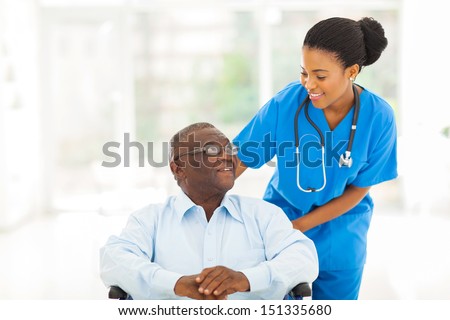 beautiful african nurse taking care of senior patient in wheelchair