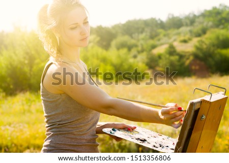 Young female artist painting a picture on canvas