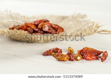 Lot of whole dry red chili pepper peperoncino on jute cloth on white wood
