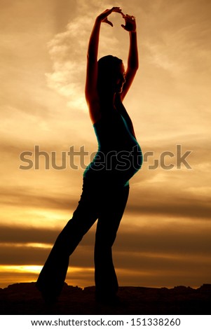 a woman is dancing pregnant silhouette in the sunset.