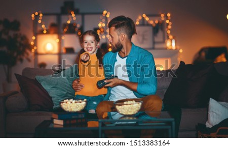 family   father and child daughter watching projector, TV, movies with popcorn in the evening   at home 
