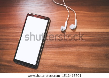 Phone with white screen and earphones at table