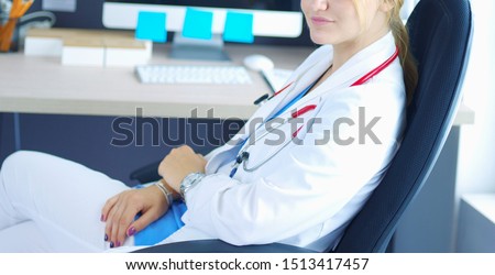 Portrait of young female doctor sitting at desk in hospital