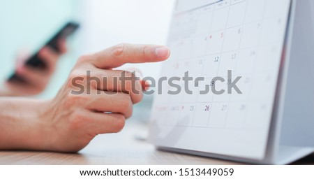 close up on employee man hand using finger pointing schedule (timetable) on calendar to make appointment meeting or manage timetable each day , life balance concept Royalty-Free Stock Photo #1513449059