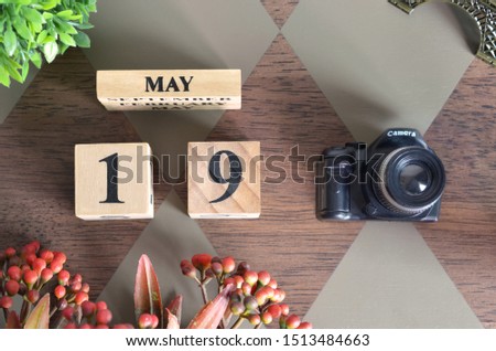 May 19, Date design with Number cube, a flower and camera on Diamond wood background.