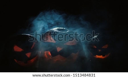 Three silhouettes of halloween jack-o-lanterns at night with burning fire inside. Pumpkins withs scary faces silhouetted 4K shot