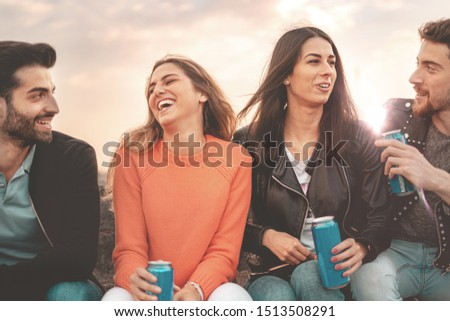 Group of young people discussing together outdoors drinking canned beers in the sunset. Royalty-Free Stock Photo #1513508291