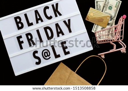 Creative promotion composition Black friday sale text on lightbox on black background, next grocery trolley, credit card, cash money. Flat lay, top view, overhead, mockup