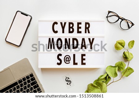 Creative promotion composition Cyber monday sale text on lightbox, laptop, mobile phone, eyeglasses, eucalyptus branch on white background. Flat lay, top view, overhead, mockup, copy space, template