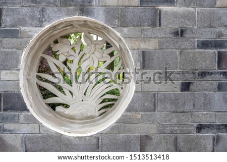 Traditional chinese stone fresco representing plants on a brick wall in HuanHuaXi public park, Chengdu, Sichuan province, China