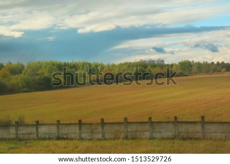Soft focus of country side view with colorful field and colorful leave on tree in autumn. View from running car's window. Nature and outdoor concept.