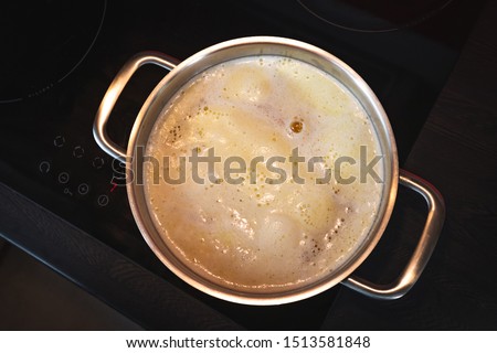 Clarification of butter, clarified butter in a steel pot on a black isolated background, top view. Royalty-Free Stock Photo #1513581848