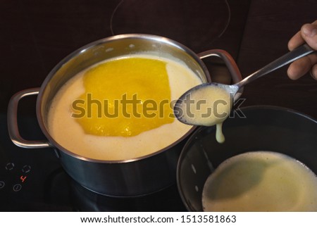 Clarification of butter, clarified butter in a steel pot mixed with steel spoon. Removing foam from butter. Royalty-Free Stock Photo #1513581863