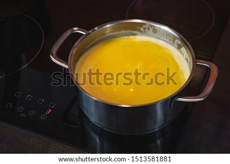 Clarification of butter, clarified butter in a steel pot. Removing foam from butter. Royalty-Free Stock Photo #1513581881