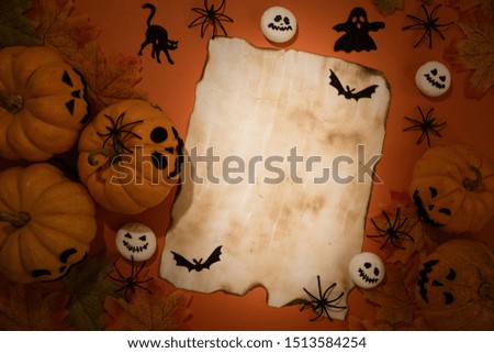 Top view of yellow ghost pumpkins with Colorful Autumn leaves and old paper on a black wooden table background. halloween concept.