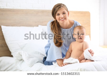 Woman and her cute little baby after bathing in bedroom