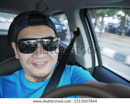 Portrait of young Asian male driver smiling happily, driver taking selfie photograph, friendly ride car sharing driver waiting for client