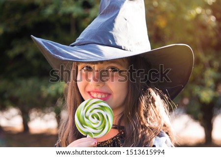 Girl dressed as a witch eating candy. happy Halloween