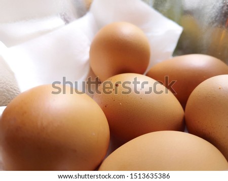 Eggs in a white basket. Many brown eggs in a plastic basket.