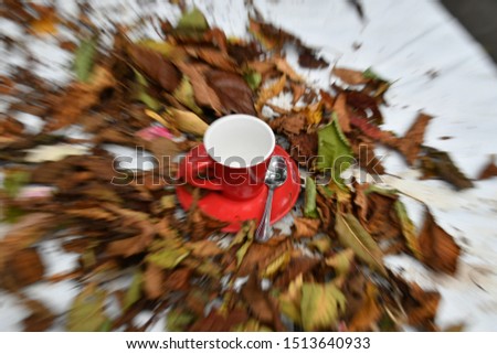 Intentionally camera zooming of autumn scene of an espresso cup on a table full of dried leaves.
Autumn  scene. 