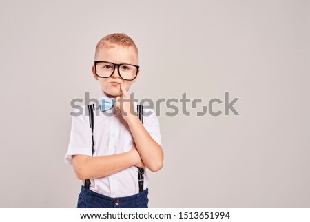 Elementary student with hand on chin thinking at studio shot 