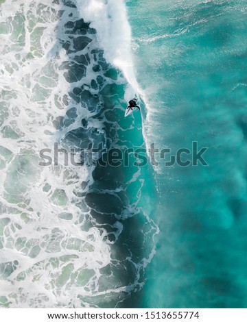 Aerial sport action shot of a surfer at sunrise riding a wave in a blue ocean in Sydney, Australia Bondi Beach
