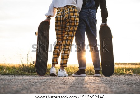Fashion Lifestyle, Happy casual young couple with skateboard, backlit at sunset