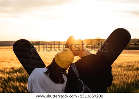 Fashion Lifestyle, Happy casual young couple with skateboard, backlit at sunset