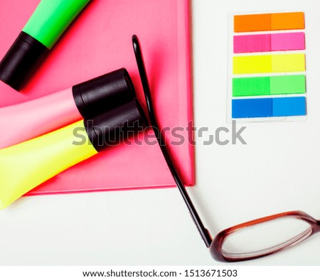 business, education and technology concept - close up of notebook, paper stickers, glasses, pencil different new stuff on white background macro isolated