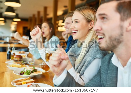 Friends as sports fans at a bar counter look at a team's game Royalty-Free Stock Photo #1513687199