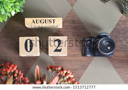 August 2, Date design with Number cube, a flower and camera on Diamond wood background.