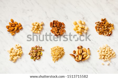Heaps of various types of nuts on the white marble background