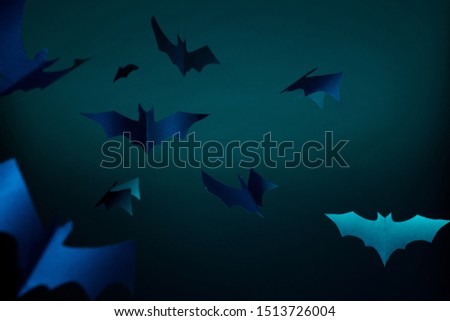 Halloween photo of blue paper bats on dark blue background.