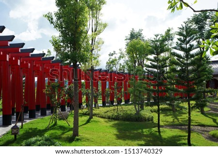 Exterior of Traditional Japanese Torii gate among green natural garden park, the iconically holy gateways that typically mark the entrance to Shinto shrines traditionally made from wood or stone