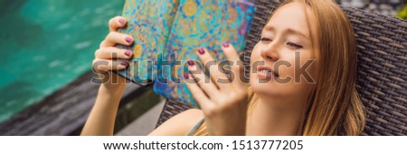 Woman reads e-book on deck chair in the garden BANNER, LONG FORMAT