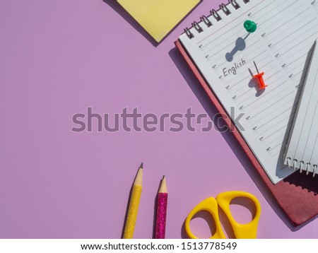 Top view office desk with Daily schedule with marked English lesson date in the calendar. Language learning concept. Pins and stationary with hard light