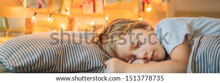 Little blond boy sleeping on a bed and home made advent calendar on a shelf. Winter seasonal tradition. Copy space BANNER, LONG FORMAT