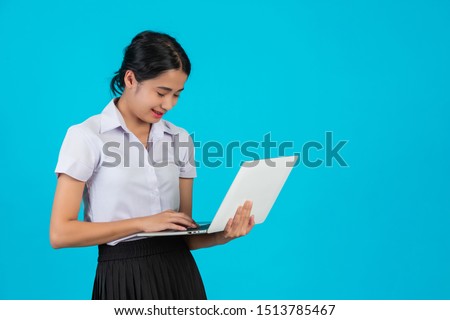 An Asian student girl holding her notebook on a blue background.