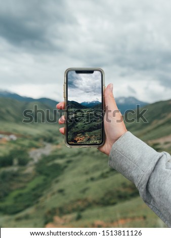 
Photo of mountains and green hills on the phone screen