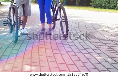 Cropped image of active senior couple walking with bycicle in park