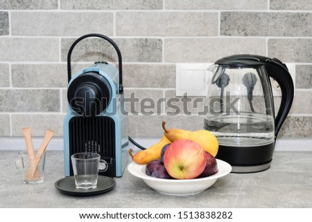 Coffee machine and electric kettle in the kitchen. Fresh fruits in white plate.
