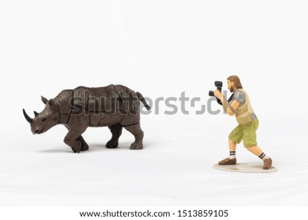 a toy photographer takes pictures of a toy rhinoceros