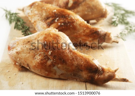 Roasted Rabbit Legs with Rosemary on a Wooden Chopping Board