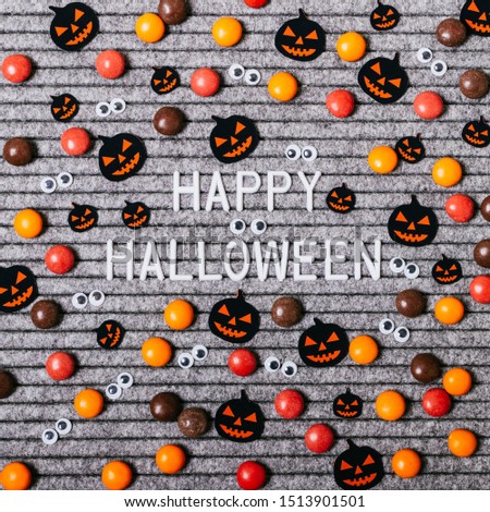 Happy Halloween text with decoration paper pumpkins and candy on a gray background. Royalty-Free Stock Photo #1513901501