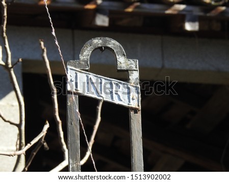 INRI written at the top edge of a rusty metal crucifix with blurred industrial background in southern France