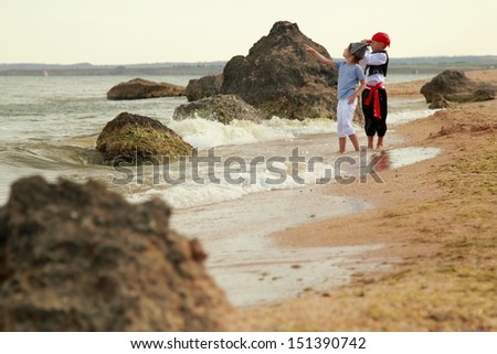 Charming young children in fancy dress playing pirates on the background of a sea landscape outdoors