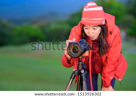 woman traveller photographer in motion of setup camera to shoot exciting shot of the sunset or sunrise on peak of mountain