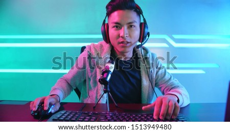 Young Asian Handsome vlogger having live stream and playing in Online Video Game Royalty-Free Stock Photo #1513949480